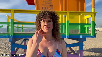 Mature Jewish woman engages in sexual activity with a stranger at the beach, wearing a bikini and using a condom